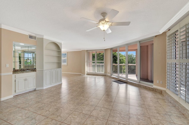 tiled empty room with a textured ceiling, built in features, ceiling fan, and crown molding