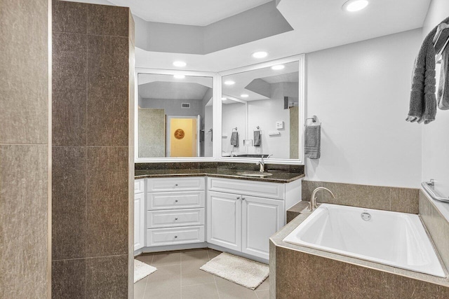 bathroom featuring tile patterned flooring, vanity, and a relaxing tiled tub