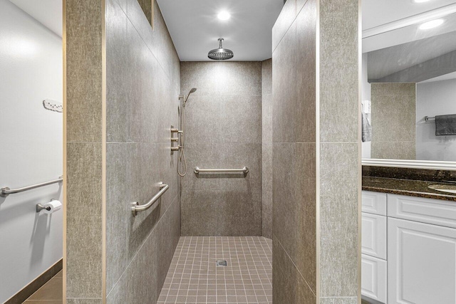 bathroom featuring tile patterned flooring, vanity, and tiled shower