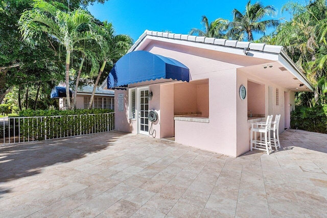 rear view of property featuring a patio area and exterior bar