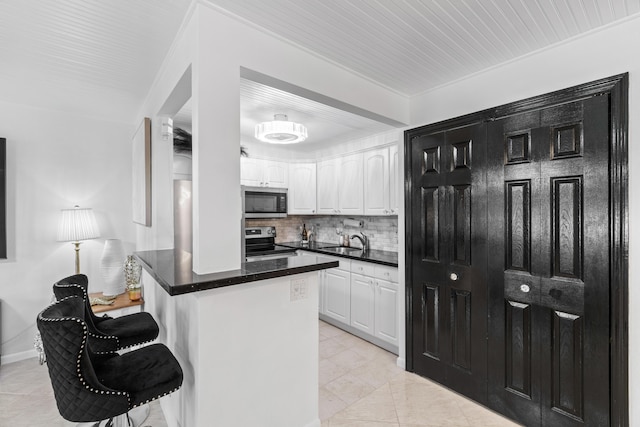 kitchen with a sink, appliances with stainless steel finishes, white cabinets, and a breakfast bar