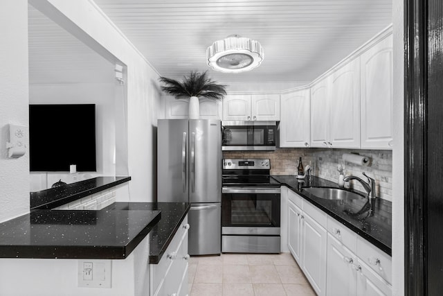 kitchen with light tile patterned floors, sink, backsplash, white cabinetry, and stainless steel appliances