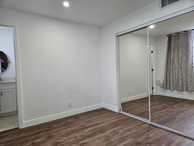 unfurnished bedroom featuring a closet and dark hardwood / wood-style flooring