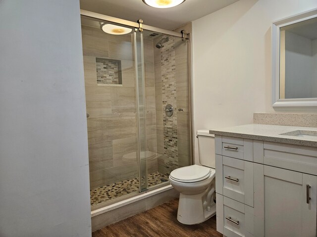 bathroom featuring hardwood / wood-style flooring, vanity, walk in shower, and toilet