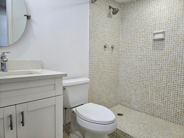 bathroom featuring a tile shower, vanity, and toilet