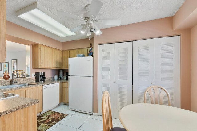 kitchen featuring light countertops, a sink, light brown cabinetry, light tile patterned floors, and white appliances