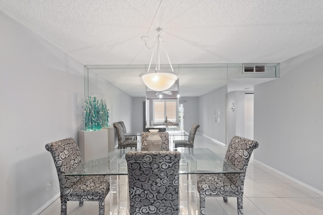 dining room with baseboards, a textured ceiling, visible vents, and tile patterned floors