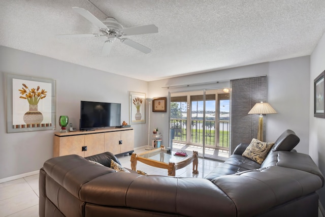 living area with light tile patterned flooring, baseboards, ceiling fan, and a textured ceiling
