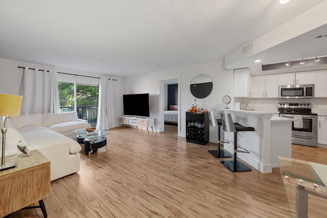 living room with track lighting, sink, and light hardwood / wood-style floors