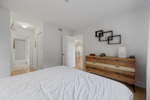 bedroom featuring light hardwood / wood-style flooring and ensuite bathroom