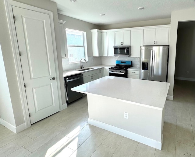 kitchen featuring sink, appliances with stainless steel finishes, tasteful backsplash, white cabinets, and a kitchen island