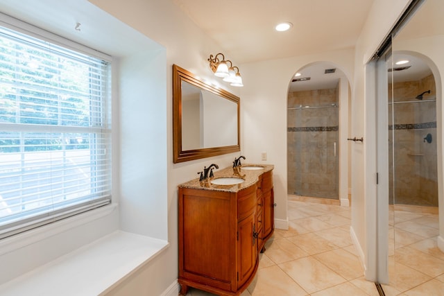 bathroom with tile patterned floors, a shower with door, and vanity