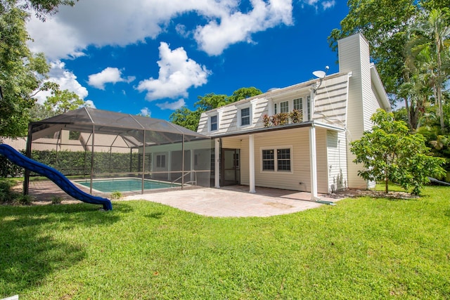 rear view of house featuring glass enclosure, a patio, and a lawn