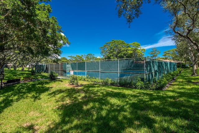 view of tennis court featuring a yard