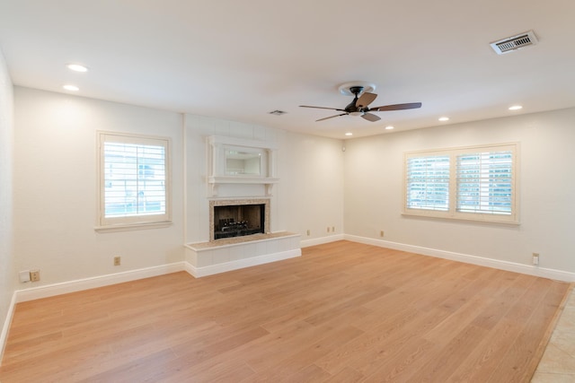 unfurnished living room with a fireplace, ceiling fan, and light hardwood / wood-style flooring