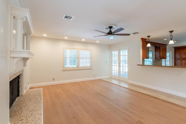 unfurnished living room featuring ceiling fan, light hardwood / wood-style flooring, french doors, and ornate columns