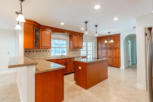 kitchen featuring sink, kitchen peninsula, decorative light fixtures, a center island, and decorative backsplash