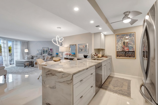 kitchen with light stone countertops, white cabinetry, sink, stainless steel appliances, and kitchen peninsula