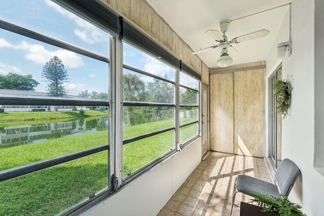 sunroom featuring ceiling fan and a water view