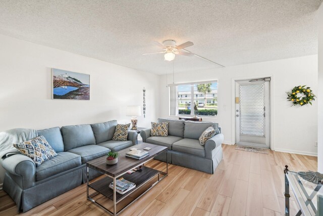 living room with ceiling fan, a textured ceiling, and light hardwood / wood-style floors