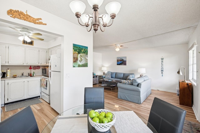 interior space featuring ceiling fan with notable chandelier, sink, light wood-type flooring, and a textured ceiling