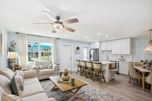 living room with ceiling fan, sink, and light hardwood / wood-style floors