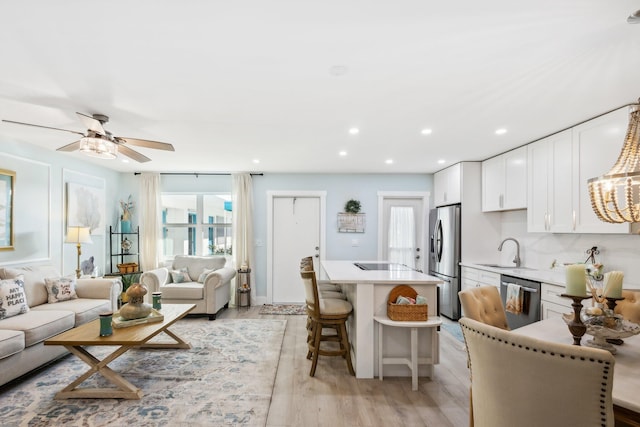 living room with sink, ceiling fan, and light hardwood / wood-style flooring