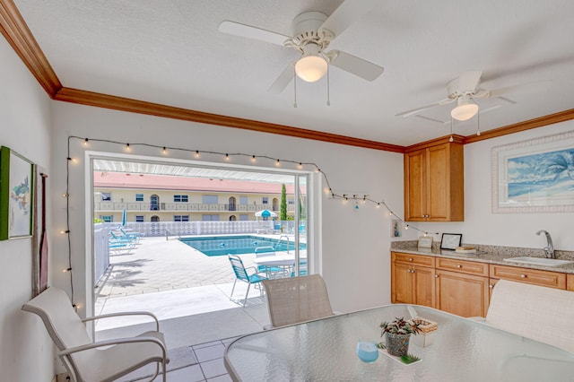 tiled dining area with ornamental molding, plenty of natural light, sink, and ceiling fan