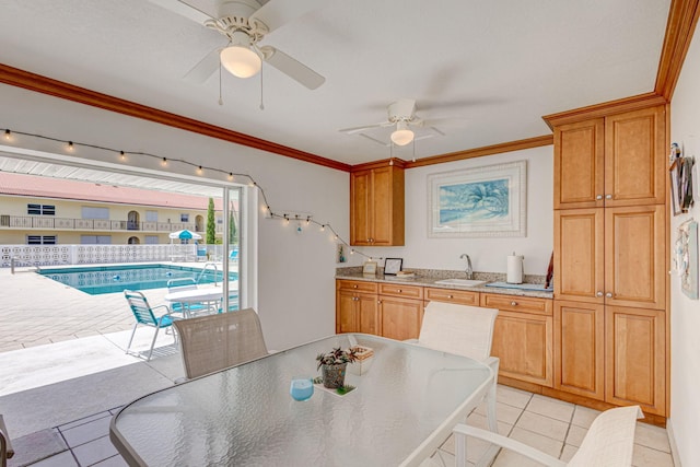 kitchen featuring crown molding, sink, light tile patterned flooring, and ceiling fan