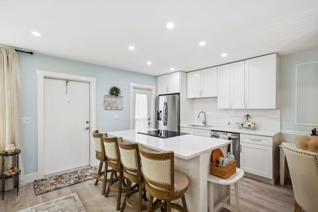 kitchen featuring white cabinetry, a breakfast bar area, light hardwood / wood-style flooring, and appliances with stainless steel finishes