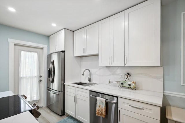 kitchen featuring stainless steel appliances, white cabinetry, sink, and tasteful backsplash