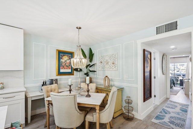 dining space featuring light wood-type flooring and a notable chandelier