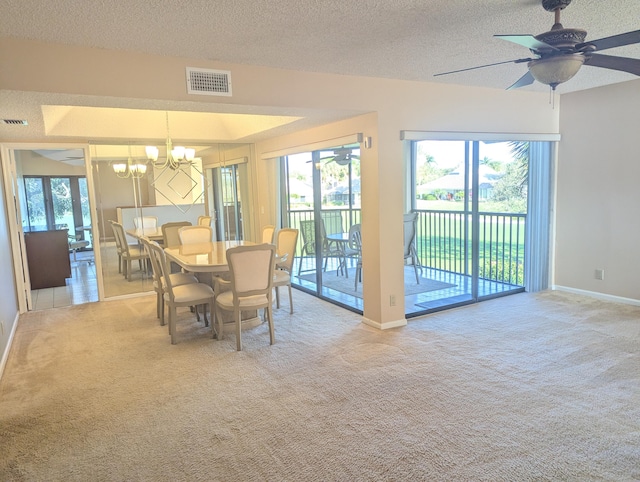 dining space with ceiling fan with notable chandelier, a textured ceiling, and light colored carpet