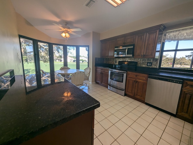 kitchen featuring lofted ceiling, decorative backsplash, ceiling fan, light tile patterned floors, and stainless steel appliances