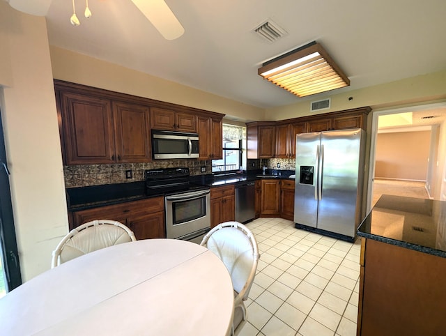 kitchen featuring backsplash, ceiling fan, light tile patterned floors, and stainless steel appliances