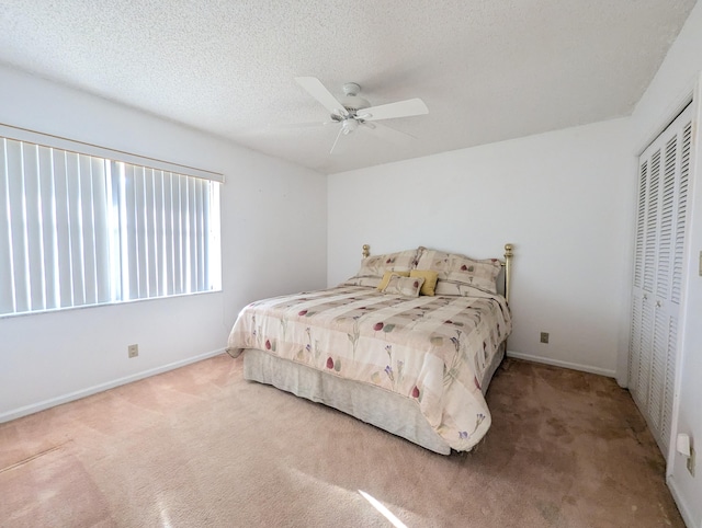 carpeted bedroom with ceiling fan, a textured ceiling, and a closet