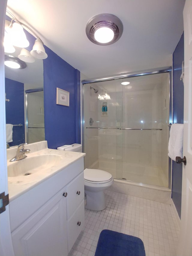 bathroom with a shower with door, vanity, and toilet