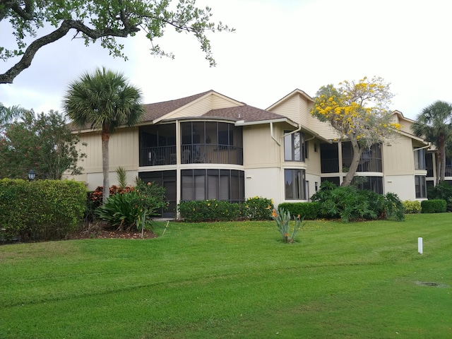 back of property featuring a sunroom and a yard