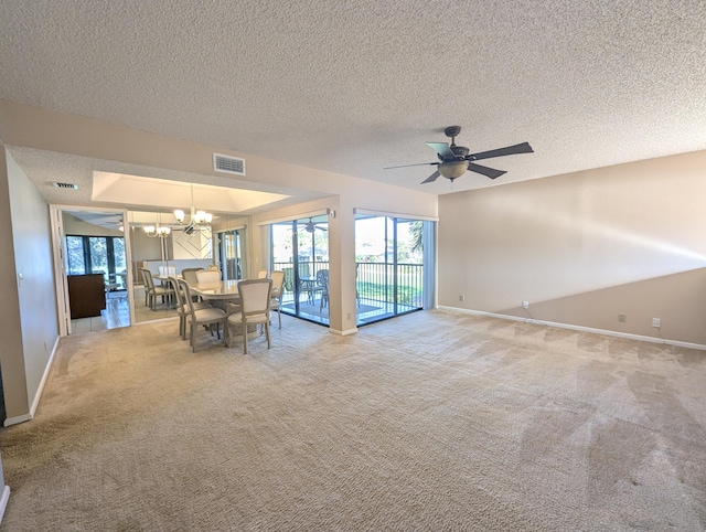 unfurnished dining area with a textured ceiling, carpet floors, and ceiling fan with notable chandelier