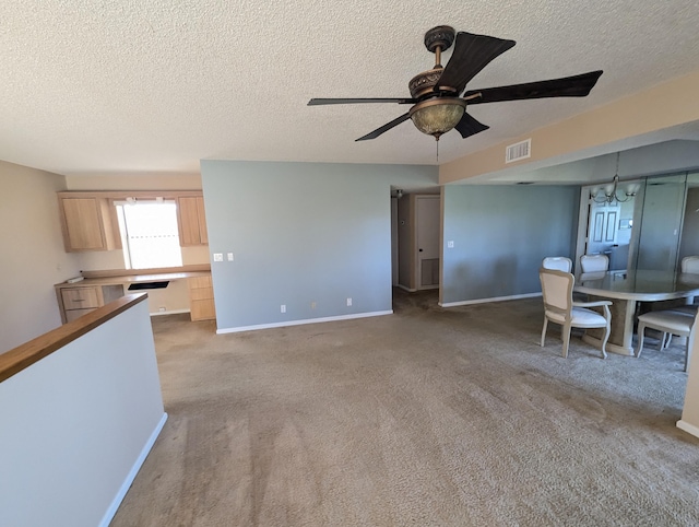 unfurnished dining area featuring light carpet, ceiling fan with notable chandelier, and a textured ceiling