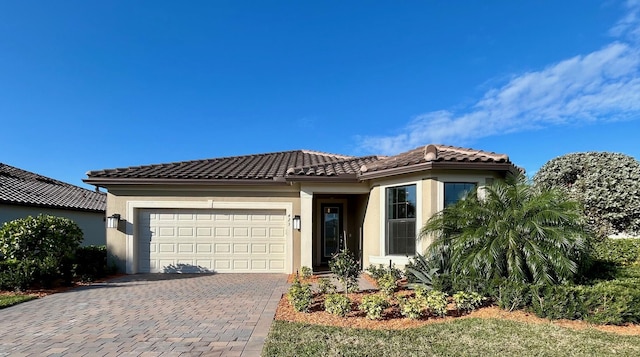 view of front of house featuring stucco siding, a tiled roof, decorative driveway, and a garage