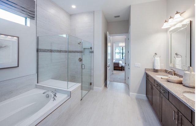 full bathroom with a shower stall, a garden tub, a healthy amount of sunlight, and a sink