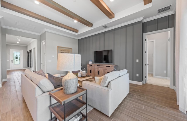 living area featuring wood finish floors, visible vents, beam ceiling, and crown molding