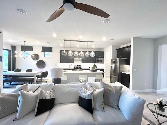 living room featuring baseboards and ceiling fan with notable chandelier