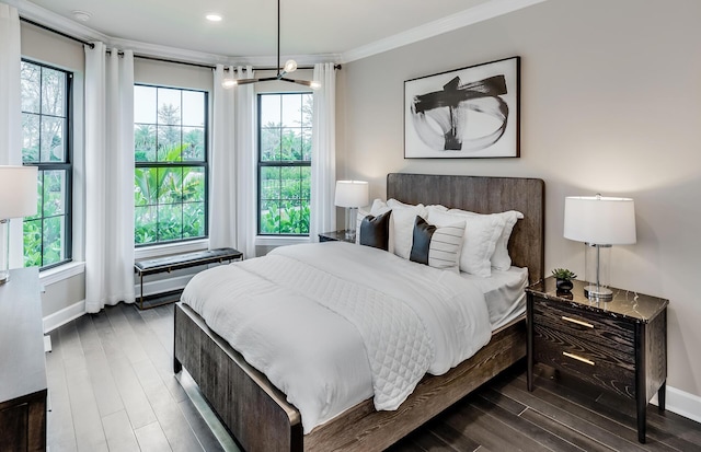 bedroom with an inviting chandelier, crown molding, baseboards, and wood finished floors