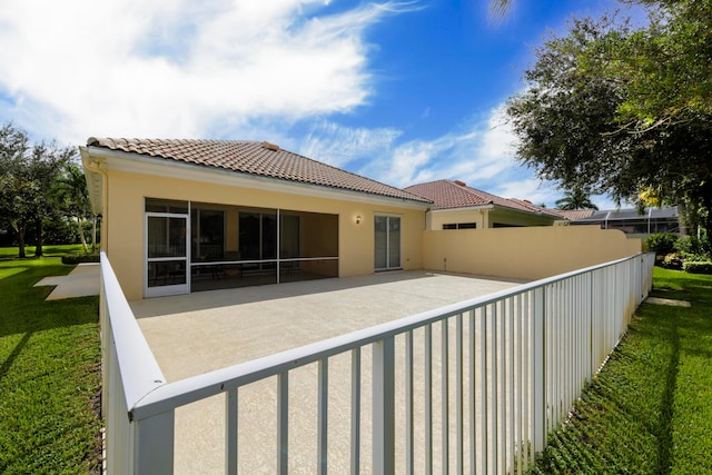 rear view of house featuring a patio, a sunroom, and a lawn