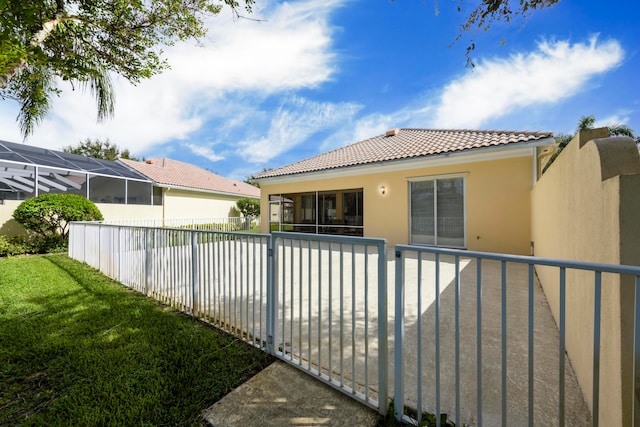 rear view of property featuring a yard and glass enclosure