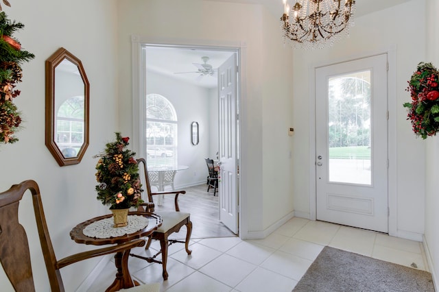 tiled foyer entrance with ceiling fan with notable chandelier