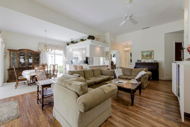 living room with hardwood / wood-style flooring and ceiling fan with notable chandelier