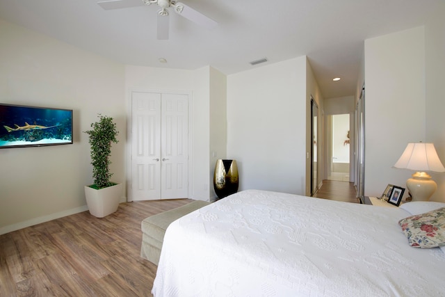 bedroom with a closet, ceiling fan, ensuite bath, and hardwood / wood-style floors